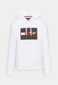 Felpa bianca con cappuccio caratterizzata da un design grafico sul petto con accenti dorati, elementi rossi e blu, tasca a marsupio e cappuccio con cordino.