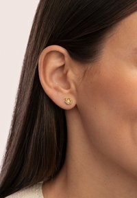 Orecchini a pendente in oro con un design floreale arricchito da pietre preziose gialle miste. L'orecchino è piccolo e delicato, con dettagli intricati.