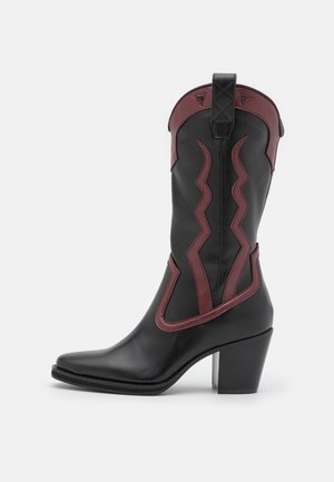 Botte de cowboy en cuir noir avec surpiqûres décoratives bordeaux et garniture, bout pointu et talon bloc empilé.