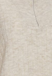 Gros plan d'un pull en maille côtelée beige avec une fermeture éclair partielle en haut au centre.
