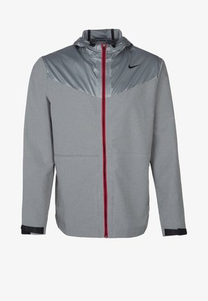 Graue Nike Herren-Sportjacke mit Kapuze, rotem Reißverschluss, schwarzem Nike-Logo auf der Brust und verstellbaren Handgelenkriemen.