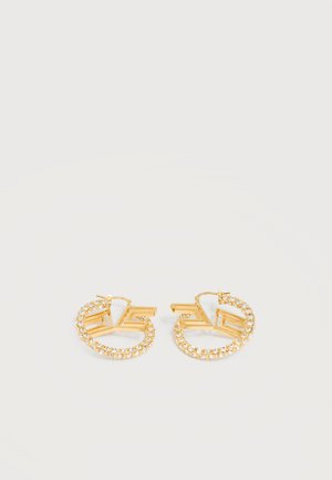 Arany karika fülbevaló beágyazott tiszta kristályokkal és geometrikus, nyitott négyzet alakú mintával világosszürke háttéren.