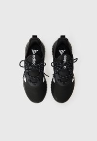 Chaussures de sport noires en matériau en maille, surface texturée, accents blancs et logo, lacets noirs avec embouts en argent, et semelle en caoutchouc rembourrée.