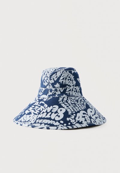 Σκούφος καπέλου τύπου bucket σε ναυτικό μπλε με ευρύ γείσο, διακοσμημένος με λευκά γράμματα και μοτίβα σε στυλ γκράφιτι σε ολόκληρο το ύφασμα.
