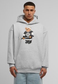 Grå hættetrøje lavet af en bomuldsblanding, der har et grafisk motiv af en bamse iført hockeyudstyr. Designet inkluderer en frontlomme og ribbede manchetter.