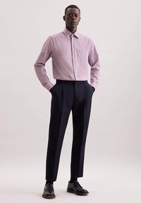 Camicia a quadri rossa e bianca con colletto a punta, abbinata a pantaloni sartoriali blu scuro e scarpe di pelle nere. Linee pulite e design aderente.