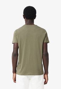 T-shirt in cotone verde oliva con collo rotondo e maniche corte, caratterizzato da un design semplice e monocolore con orlo dritto.
