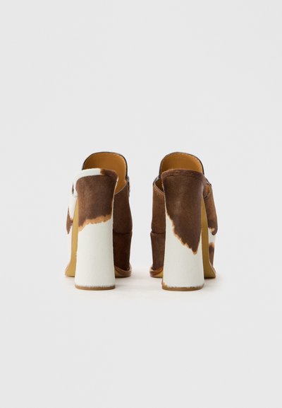 Pantofi cu toc înalt din piele de vacă maro și alb, cu toc pătrat. Design deschis la spate. Model texturat din blană pe exterior. Căptușeală interioară netedă.