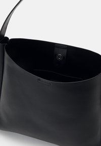 Sac à épaule en cuir noir avec une large ouverture et une texture lisse. Dispose d'une poche interne et d'un fermoir à pression. Design simple.