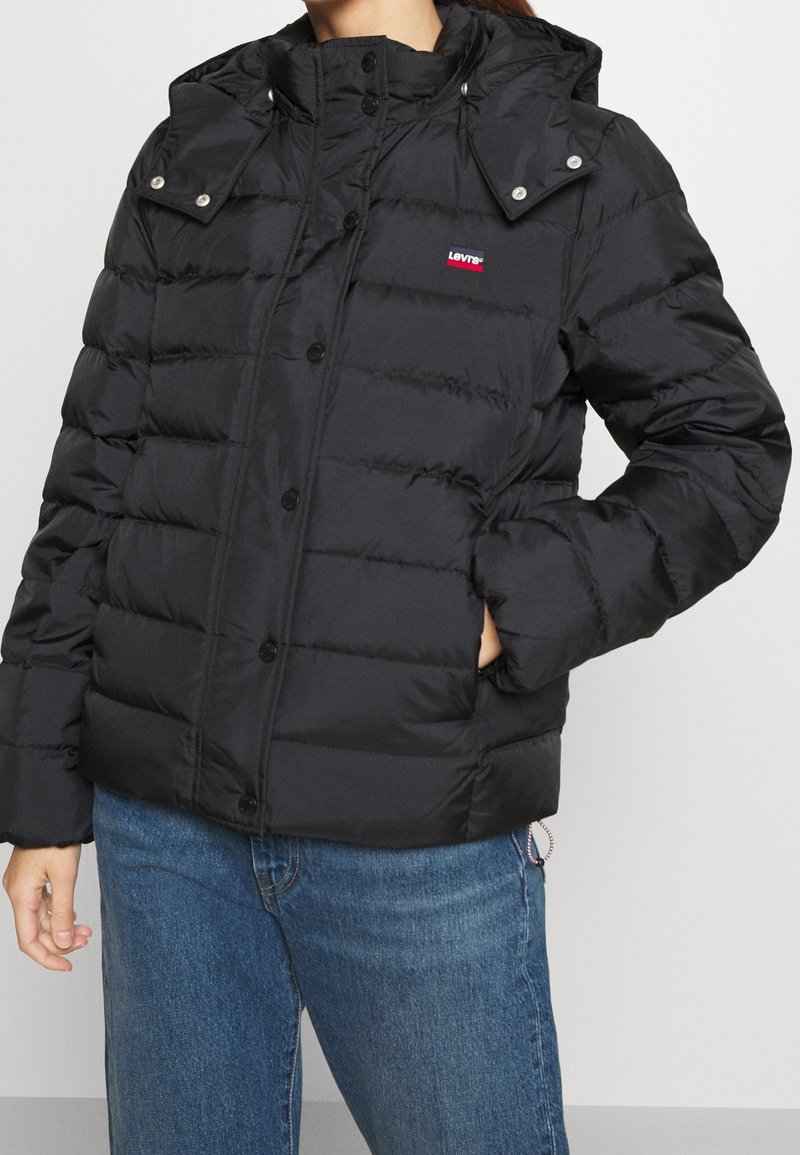 Black puffer jacket with a hood, featuring a quilted design, snap buttons, and a small Levi's logo on the left chest.