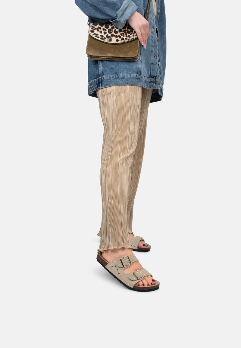Pantalons beiges plissés, veste en denim oversize, sandales grises avec double boucle, et un sac bandoulière à imprimé léopard. Détails de texture et de couleur visibles.
