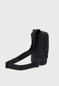 Μαύρη τσάντα ώμου με υφή, κλείσιμο με φερμουάρ, ρυθμιζόμενο λουρί και διακριτικό γεωμετρικό μοτίβο στο ύφασμα. Κομψός και ορθογώνιος σχεδιασμός.