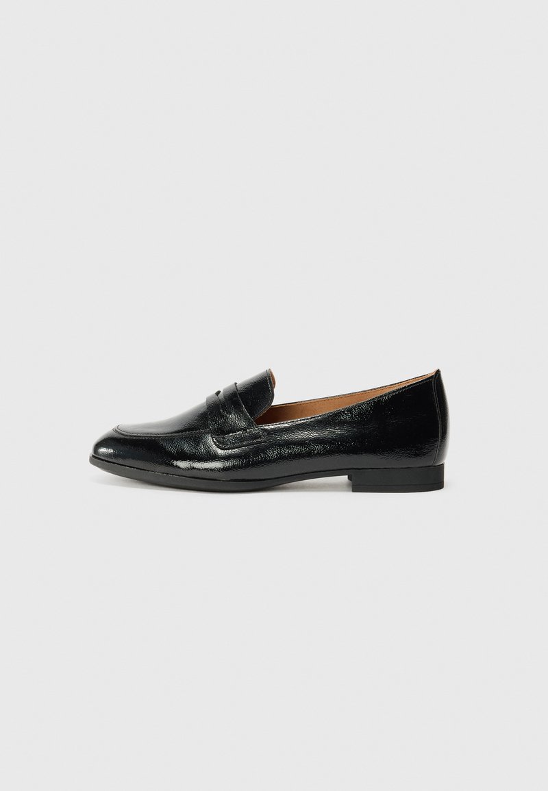 Des mocassins en cuir noir avec un petit talon, une texture lisse et brillante, un bout pointu et une sangle décorative sur le devant.