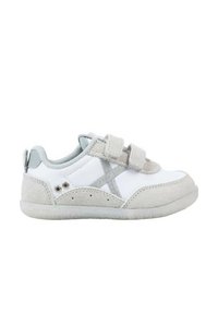 Zapatilla blanca con detalles en ante gris, correas con gancho y bucle, forro de malla y suela de goma texturizada, que presenta pequeñas perforaciones y detalles de logotipo.
