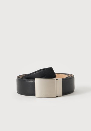 Ceinture en cuir noir enroulée avec boucle rectangulaire argentée lisse sur fond blanc uni.