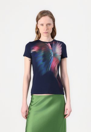 Navy t-shirt with a colorful abstract design; short sleeves, crew neck, and soft fabric. Paired with a shiny green satin skirt.