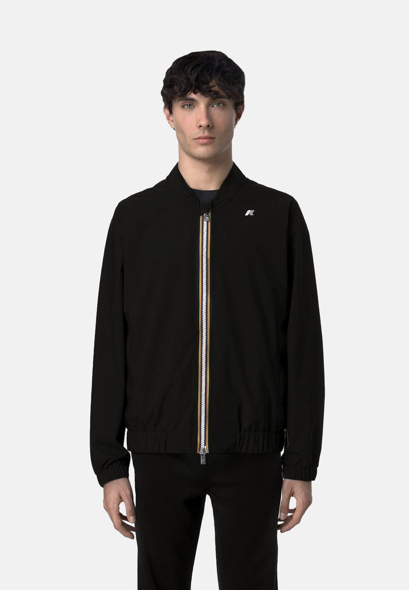 Giubbotto bomber nero con zip frontale, strisce colorate, polsini e orlo a costine, e un piccolo logo sul petto. Materiale leggero.