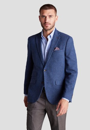 Männer Sakko in Blau mit Fischgrätmuster, mit Reverskragen, zwei Knöpfen, Fronttaschen und strukturierter Oberfläche, kombiniert mit einem hellblauen Hemd.