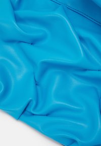 Materiale morbido, strutturato, di un blu brillante con una finitura liscia e lucida, che presenta drappeggi e pieghe sottili.