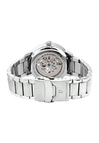 Montre en acier inoxydable avec un fond transparent, bracelet en argent et fermoir. Mouvement mécanique visible à travers le dos.