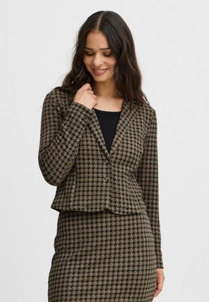 Braun karierter Blazer im Hahnentrittmuster mit langen Ärmeln, tailliertem Schnitt und Knopfverschluss. Über einem schwarzen Oberteil getragen.