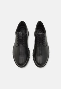Black leather shoes with a smooth finish, round toe, and six-eyelet lace-up design; textured rubber sole with a tread pattern.