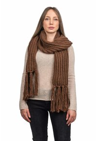 Sciarpa lavorata a maglia marrone con frange, caratterizzata da una consistenza grossa e una forma ampia e rettangolare, avvolta attorno al collo di una persona.