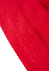 Red fleece fabric with a soft texture, featuring embossed text "CAMPDAILD" and minimalistic design.