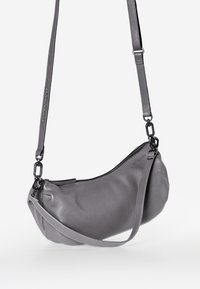 Borsa a spalla in pelle grigia con finitura testurizzata, forma curva, chiusura con zip e tracolla regolabile. Presenta dettagli in metallo nero.
