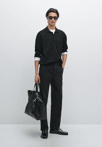 Schwarzes gestricktes Poloshirt, weißes Unterhemd, schwarze Hose, Ledertasche und schwarze Schuhe. Slim Fit mit einem klaren Design und strukturierter Silhouette.