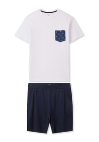 T-shirt bianca a maniche corte con tasca blu navy decorata con un motivo di palme, abbinata a pantaloni corti blu navy con elastico in vita e tasche laterali.