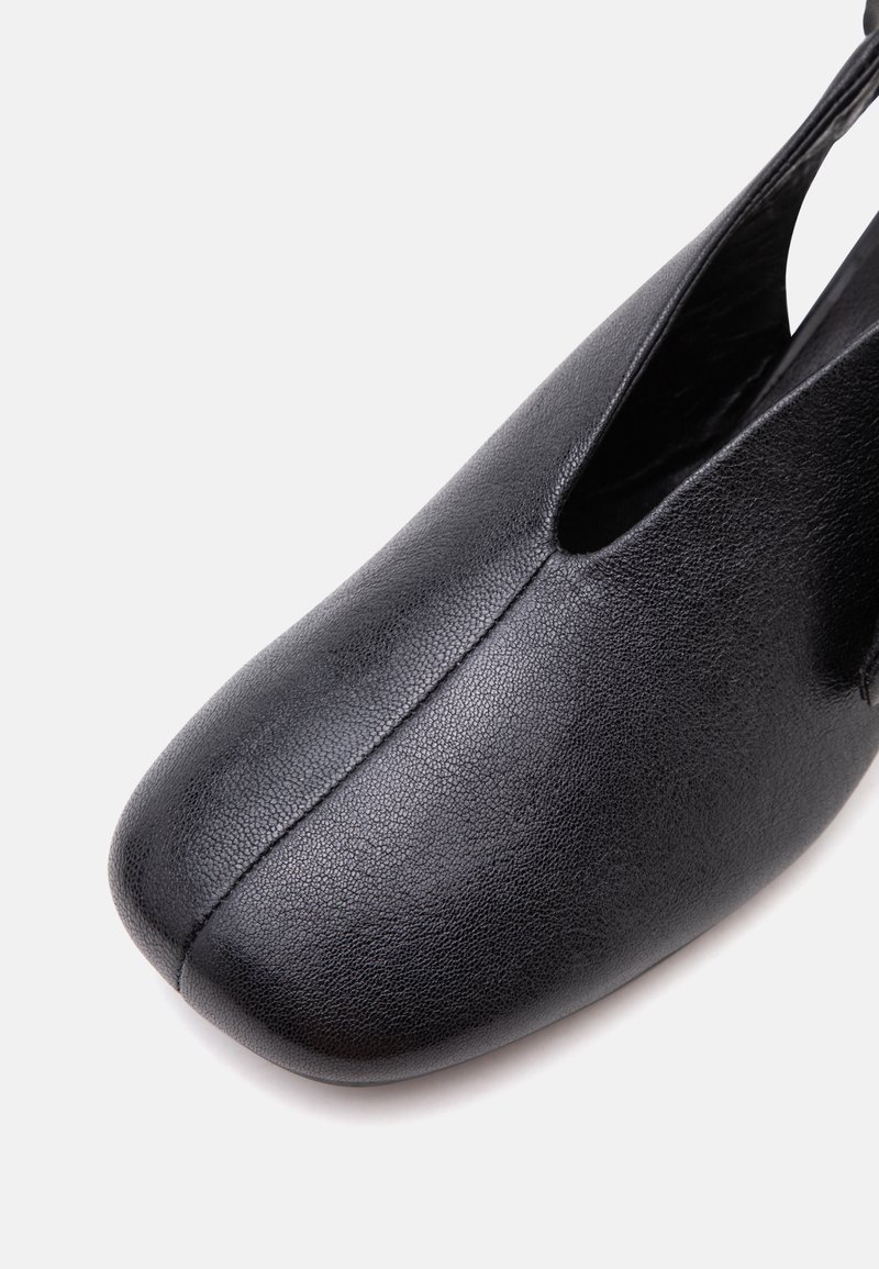 Schwarzer Lederschuh mit abgerundet quadratischer Spitze und einer zentralen Naht, die vom Zeh bis zur Öffnung verläuft.