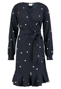 Robe portefeuille bleu marine à pois blancs, manches longues avec poignets élastiques, taille nouée et ourlet à volants. Texture de tissu douce.