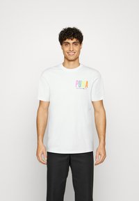 Bílý tričko s krátkým rukávem vyroben�é z bavlny. Má vícebarevné logo Puma na levé hrudi a kulatý výstřih.