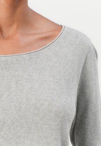 Gray long-sleeve top featuring a wide scoop neckline and soft, textured fabric. Close-up view highlighting the neckline and sleeve detail.