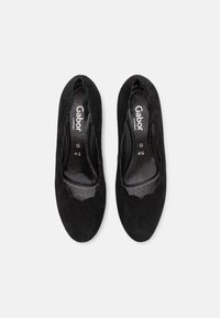 Svarta mocka slip-on skor med en slät yta, rund tå och scalloped kant; märkta innersulor har perforerat mönster.