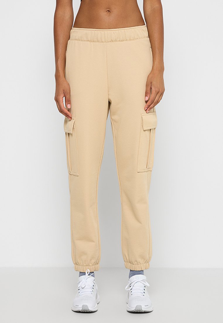 Pantalons de survêtement cargo beiges avec une taille élastique, des poignets fuselés et deux poches latérales. Fabriqués dans un tissu doux avec une texture lisse.