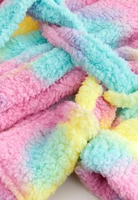 Couverture en polaire duveteuse multicolore avec des sections pastel rose, bleu, jaune et violet, présentant une surface douce et texturée.