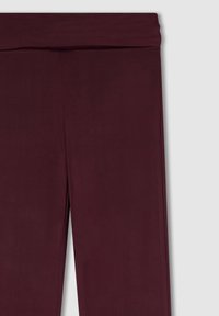 Leggings bordeaux con una texture liscia, caratterizzati da un ampio elastico in vita e un design aderente che arriva fino alle caviglie.