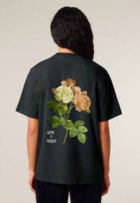 Black t-shirt featuring a floral graphic of pink and cream roses with green leaves. Text reads "LOVE & ROSES" in white. Short sleeves, relaxed fit.
