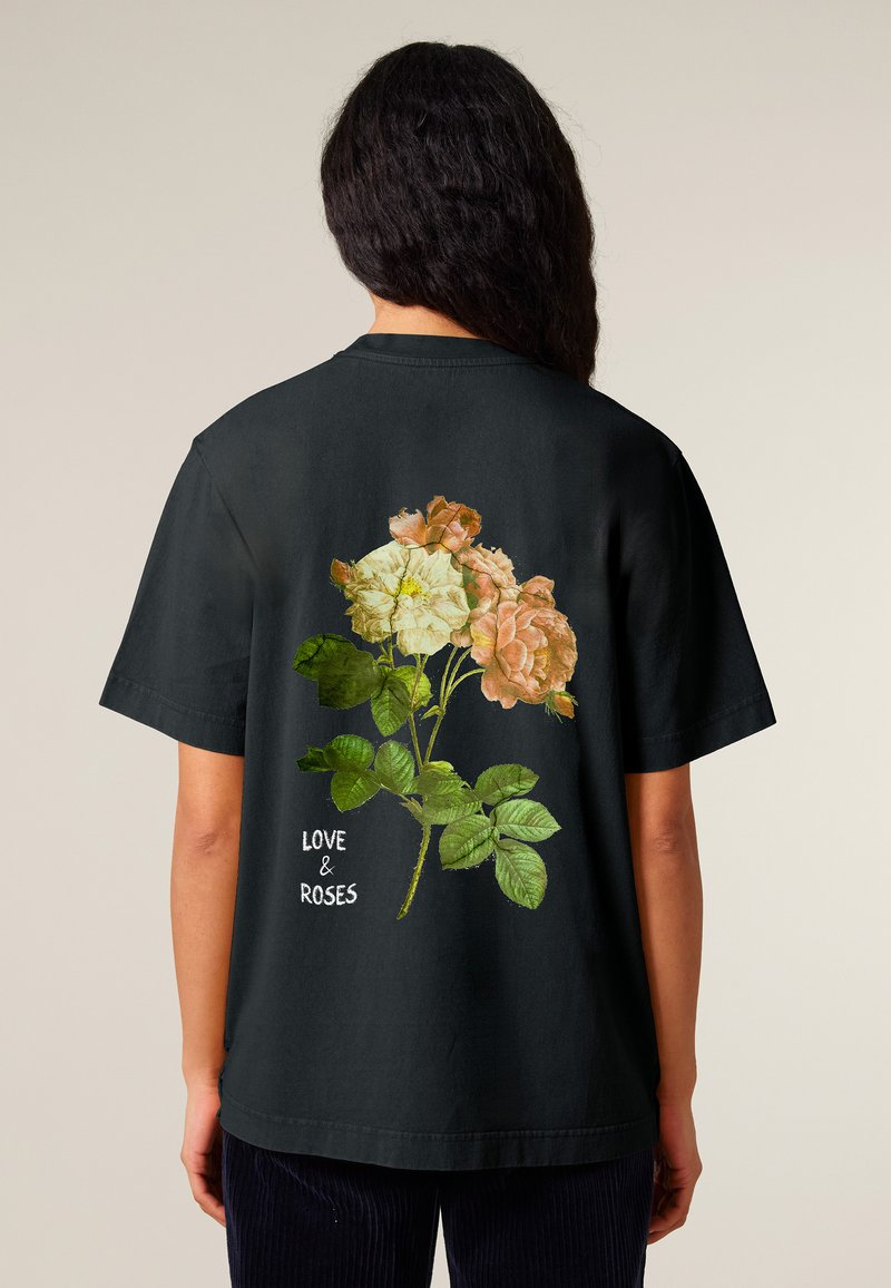 Black t-shirt featuring a floral graphic of pink and cream roses with green leaves. Text reads "LOVE & ROSES" in white. Short sleeves, relaxed fit.