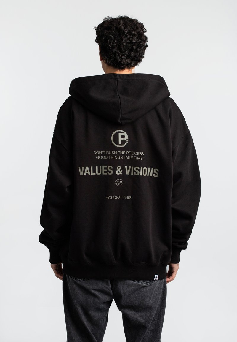 Sort hættetrøje med stort rygprint i lysegrå. Har et logo, tekst og en kengurulomme. Stoffet ser blødt og afslappet ud.