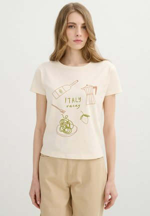 Joven mujer con camiseta beige con ilustraciones de botella de vino, cafetera moka, tenedor con pasta, limón y texto "ITALY vacay"