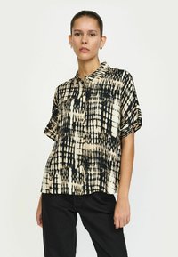 Cămașă cu mânecă scurtă, în nuanțe de crem și negru, prezentând un model abstract îndrăzneț. Guler butonat, croi lejer și textură netedă.