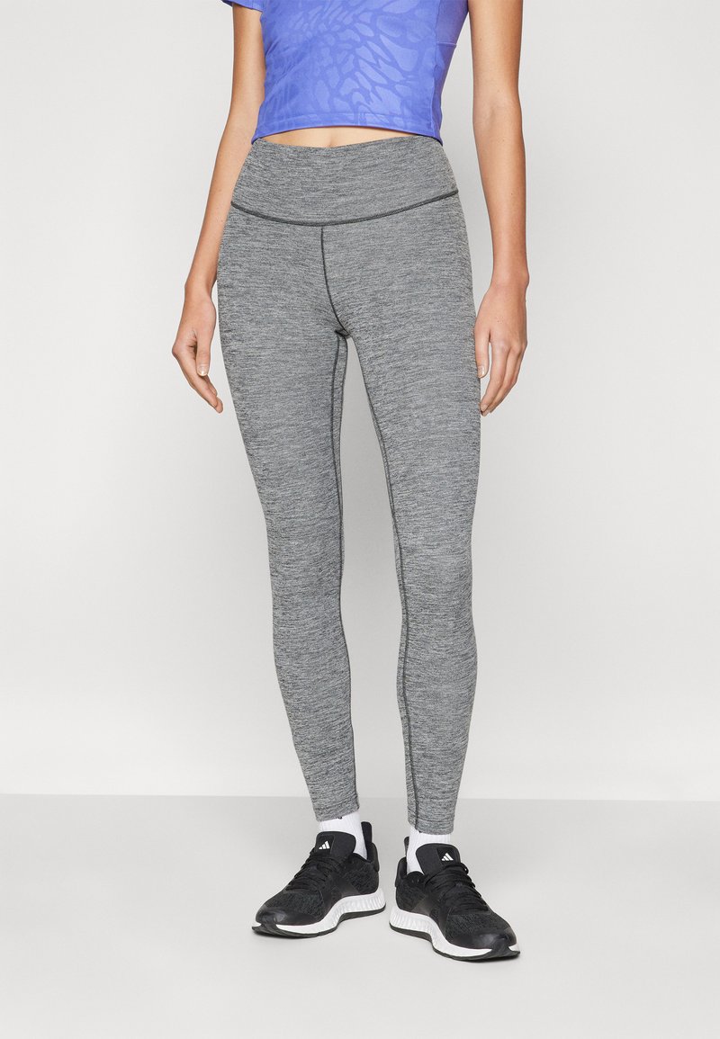 Grå leggings av texturerat tyg, hög midja, kombinerat med en blå mönstrad crop top och svarta joggingskor.