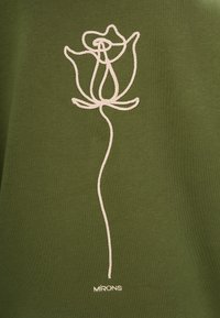 Groene stoffen T-shirt met een witte geborduurde rozenontwerp. De tekst "MIRONS" staat ook onderaan in het wit.