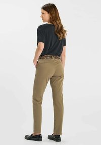 Pantalon beige à coupe ajustée, avec une ceinture à imprimé léopard et un haut noir à manches courtes, vu de dos. Texture lisse, style décontracté.