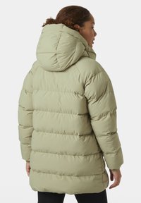 Parka acolchada de un verde claro con capucha, que presenta secciones acolchadas horizontales, puños elásticos y un dobladillo trasero ligeramente más largo.