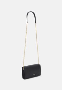 Sac en cuir noir à porter en bandoulière avec une chaîne dorée, de forme rectangulaire, surface texturée et logo sur le devant.