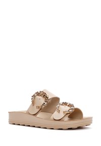 Beige slide sandals made of smooth material, featuring two wide straps with embellished golden hardware and textured rubber soles.